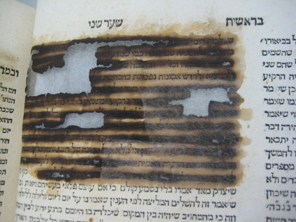 Photo of a page with Hebrew script redacted with iron gall ink.