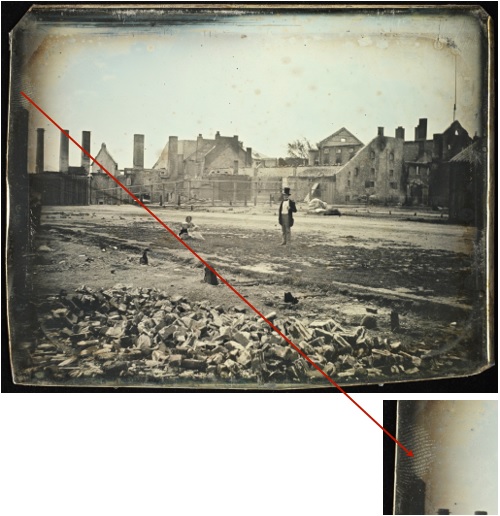 A landscape image of a burnt building. A man in a top hat in the centre and a woman sitting on the ground off to the left. This photograph has a finger mark in the top left corner. A close-up of a finger print.