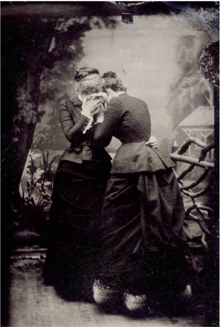 Two women standing, holding each other, while crying.