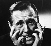 Photo noir et blanc de Gratien Gélinas, visage dans les mains, avec une cigarette.
