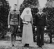 Photographie noir et blanc d’une infirmière militaire aux côtés de deux soldats.